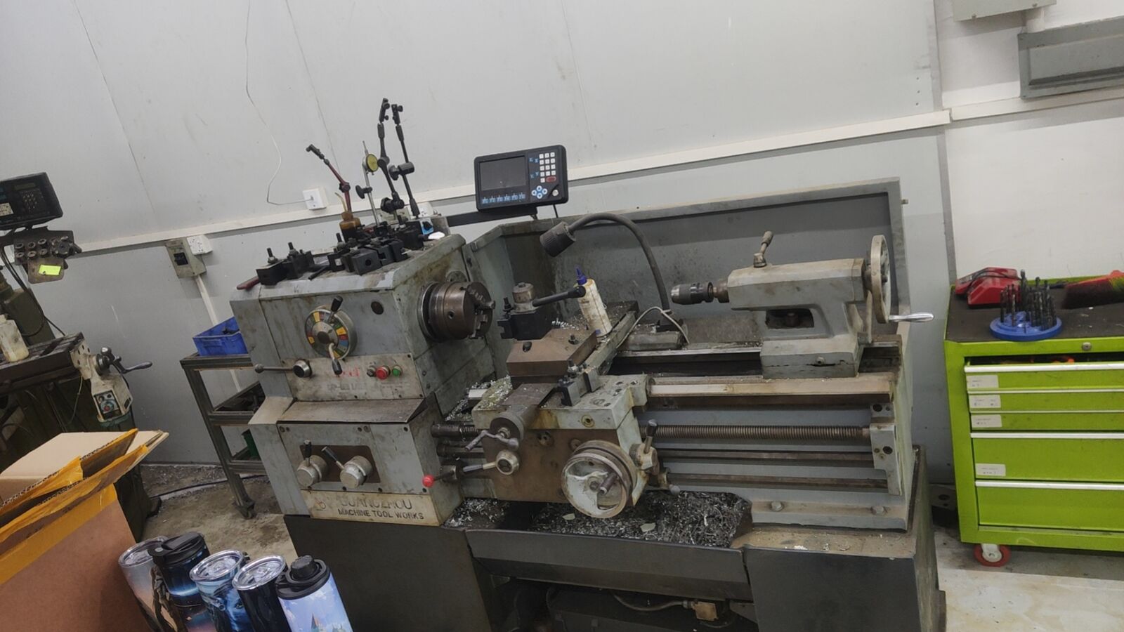A small machine shop in China with a manual lathe and milling equipment on a crowded floor.